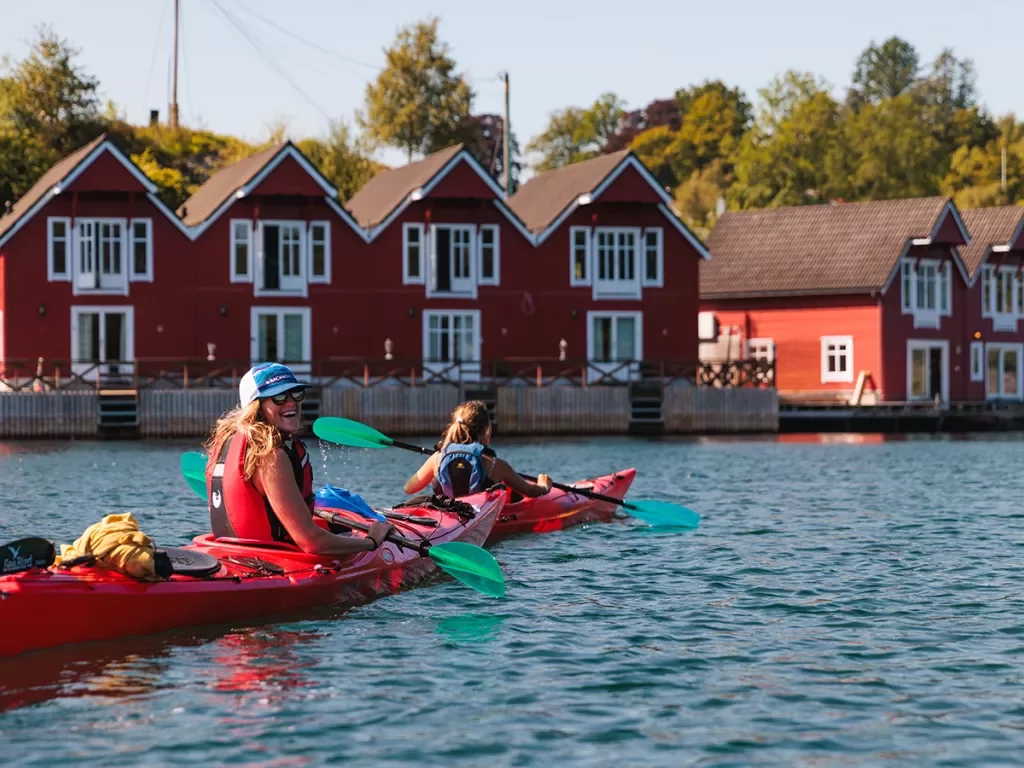 Two woman in kayaks paddling toward a dock