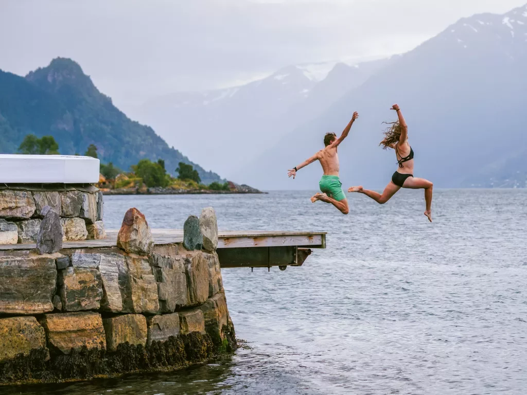 two guest jump off a dock into water