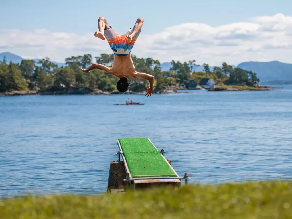 Man backflipping from the ledge into a lake