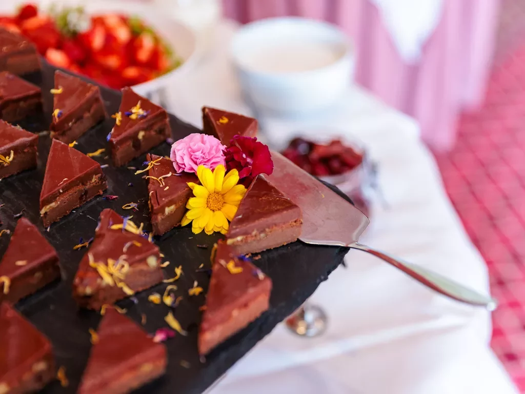 Plate full of triangular chocolate pastries with flowers scattered