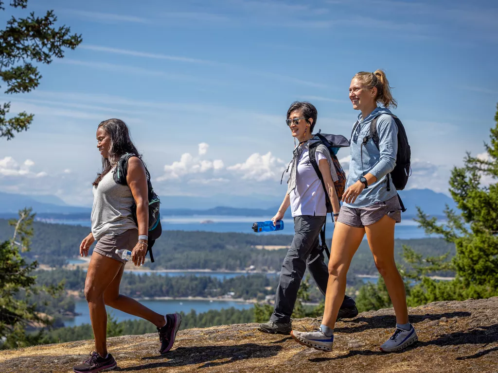 Group of three women hiking down a dirt path on a hill