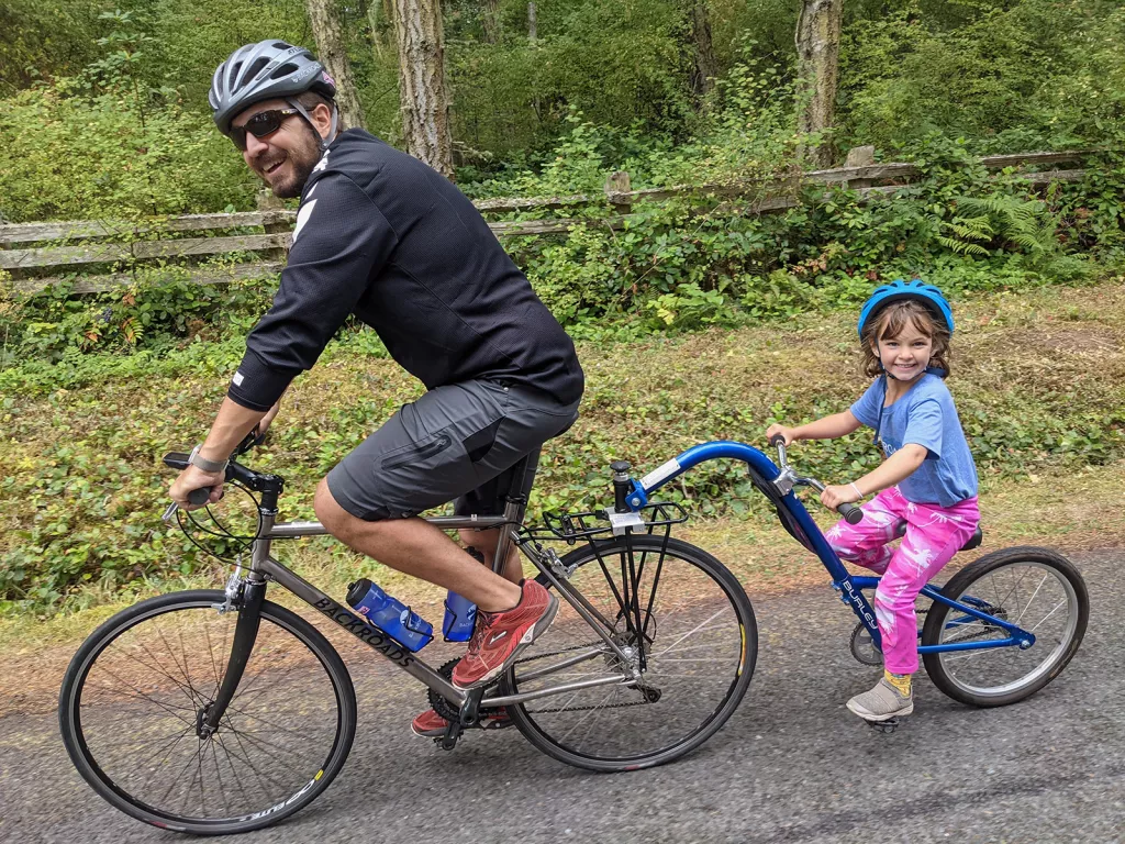 Man and a toddler riding a tandem bike on an asphalt road