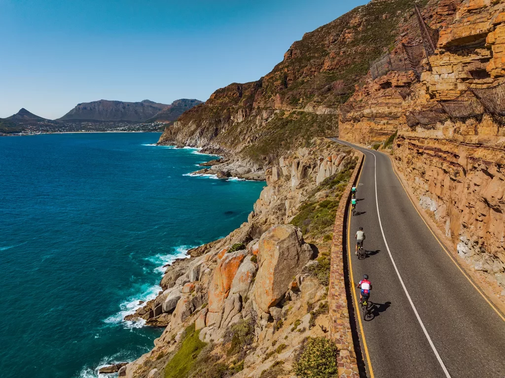 people riding bicycles down a beachfront road