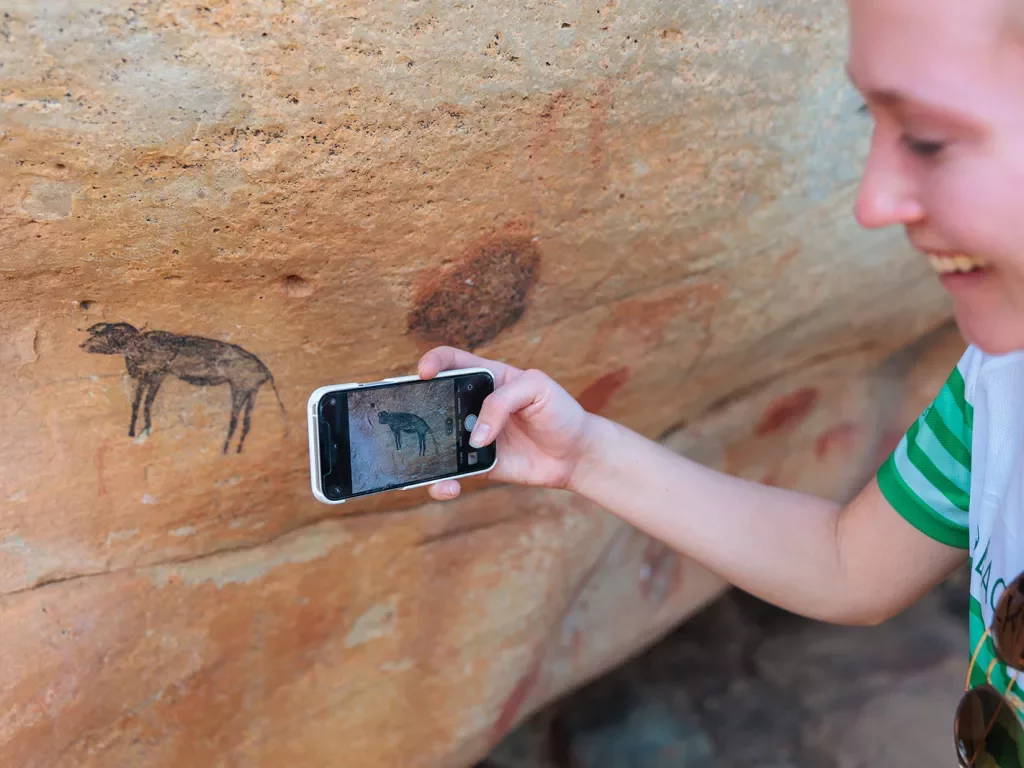 A person takes a photo of cave drawings