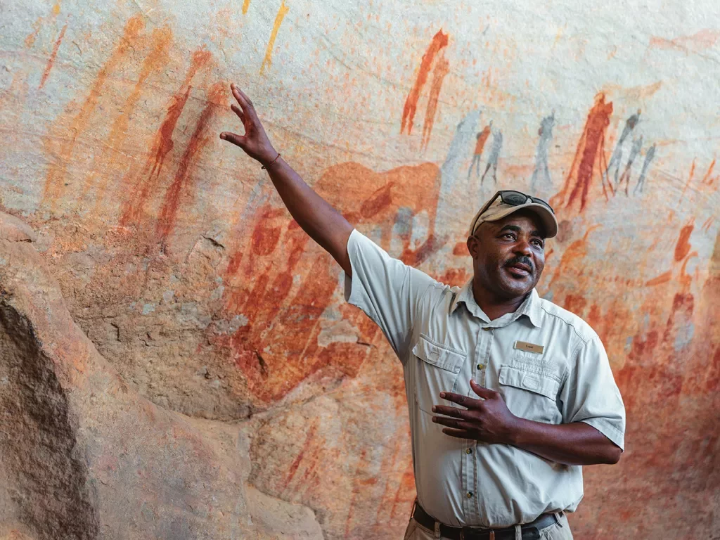 A man points to cave paintings on a wall