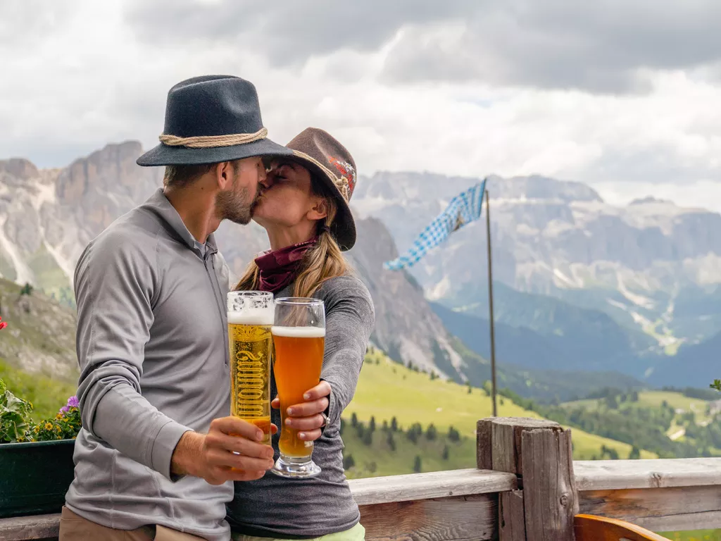 Man and woman kissing while holding up glasses of beer