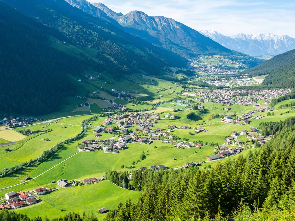 Small town scattered across a large grass valley, surrounded by large mountains