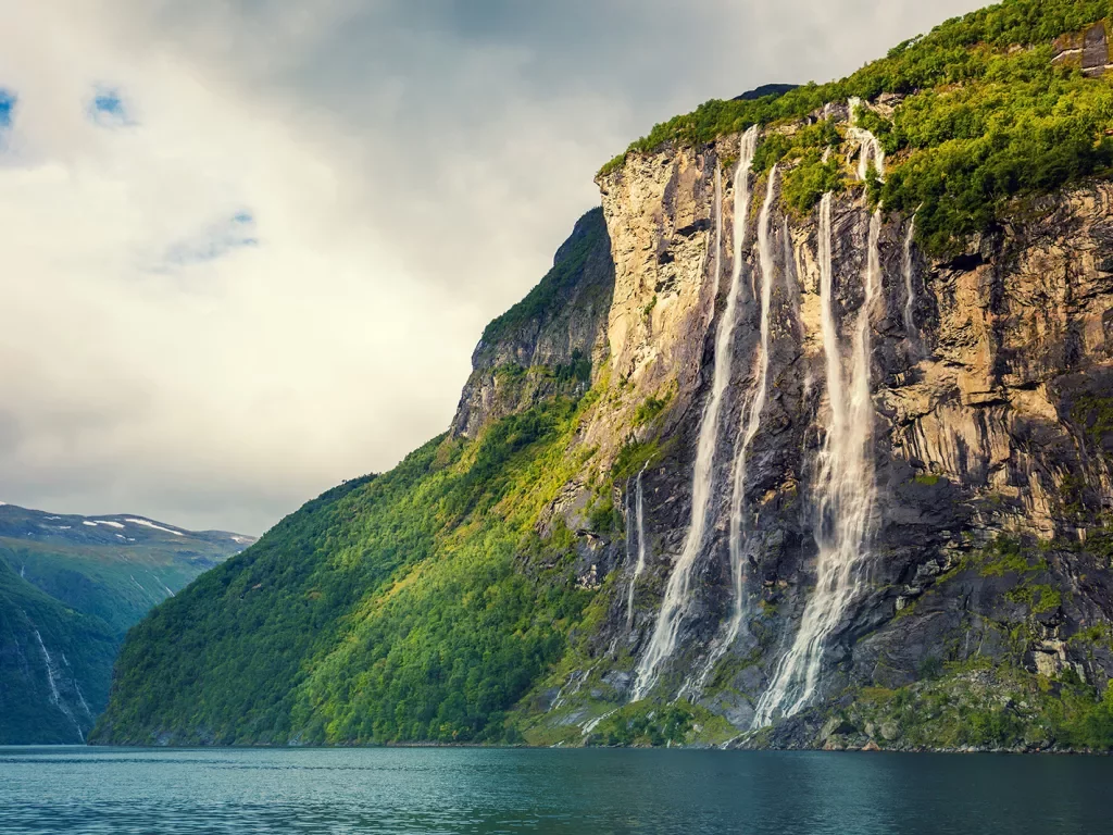 Cliff covered in trees with a waterfall in between