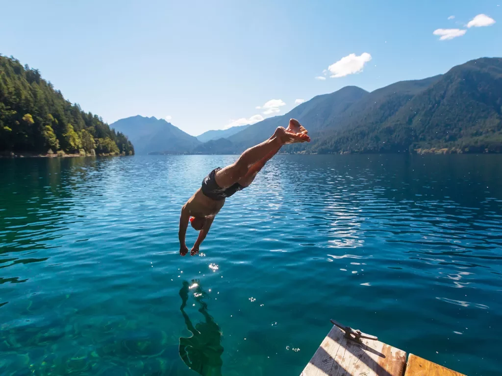 Man diving into a lake from a wooden port