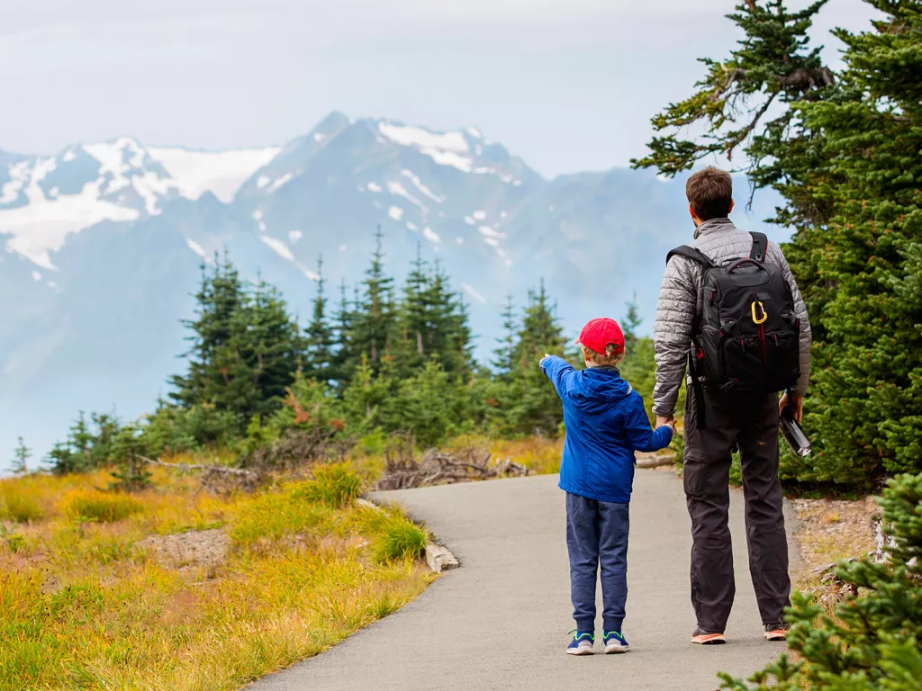 Man and child pointing at snow-capped mountains in the distance