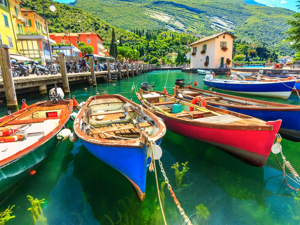 Multiple colorful boats tied to a dock by the ocean