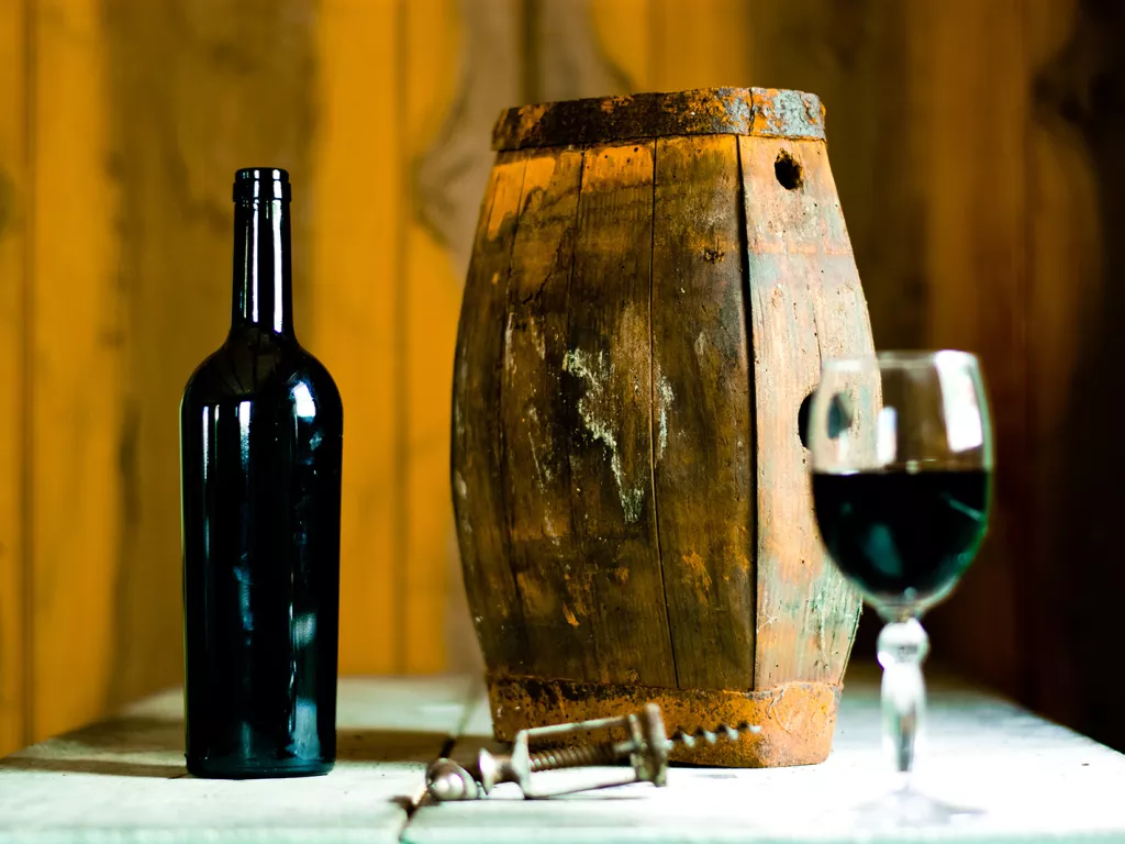 Barrell next to an open bottle of wine and a wine glass