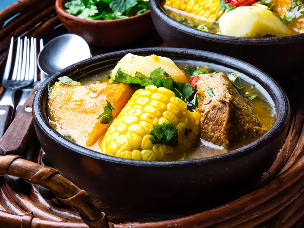 Bowl of soup filled with corn, meat and other vegetables