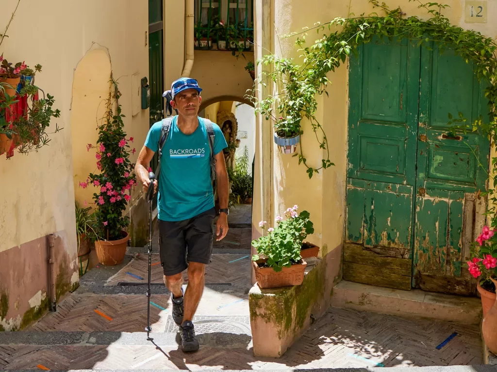 Man with a walking pole going through alleyways of a town