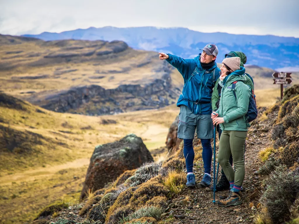 Man and two people pointing at an empty valley