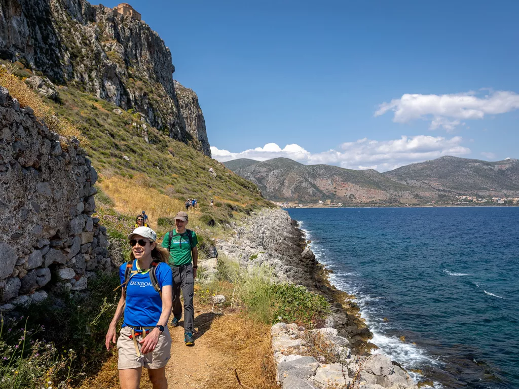 Group of people hiking on a gravel path next to the ocean