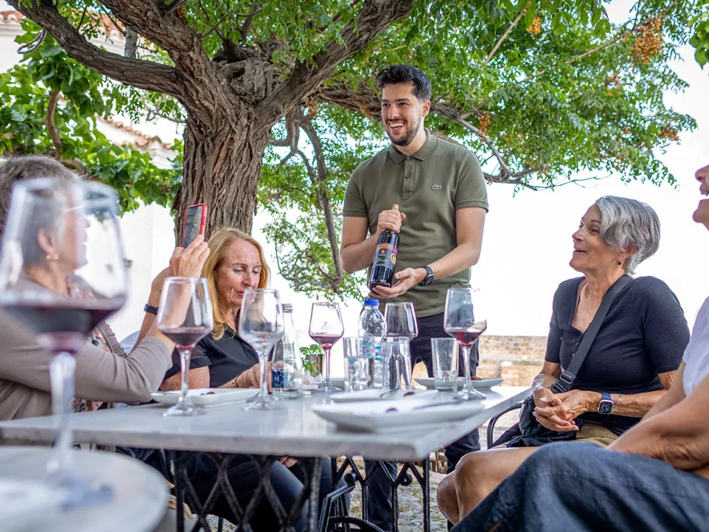 One man holding a wine bottle around four women siting down