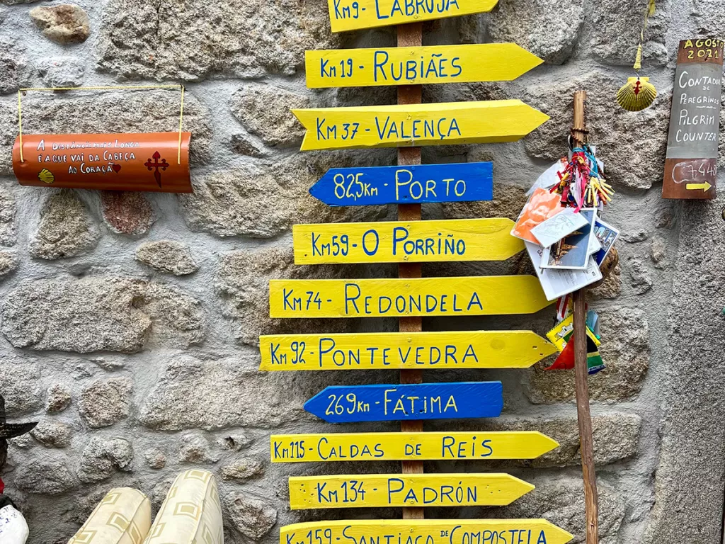 A sign against a stone with with yellow and blue arrows pointing in different directions