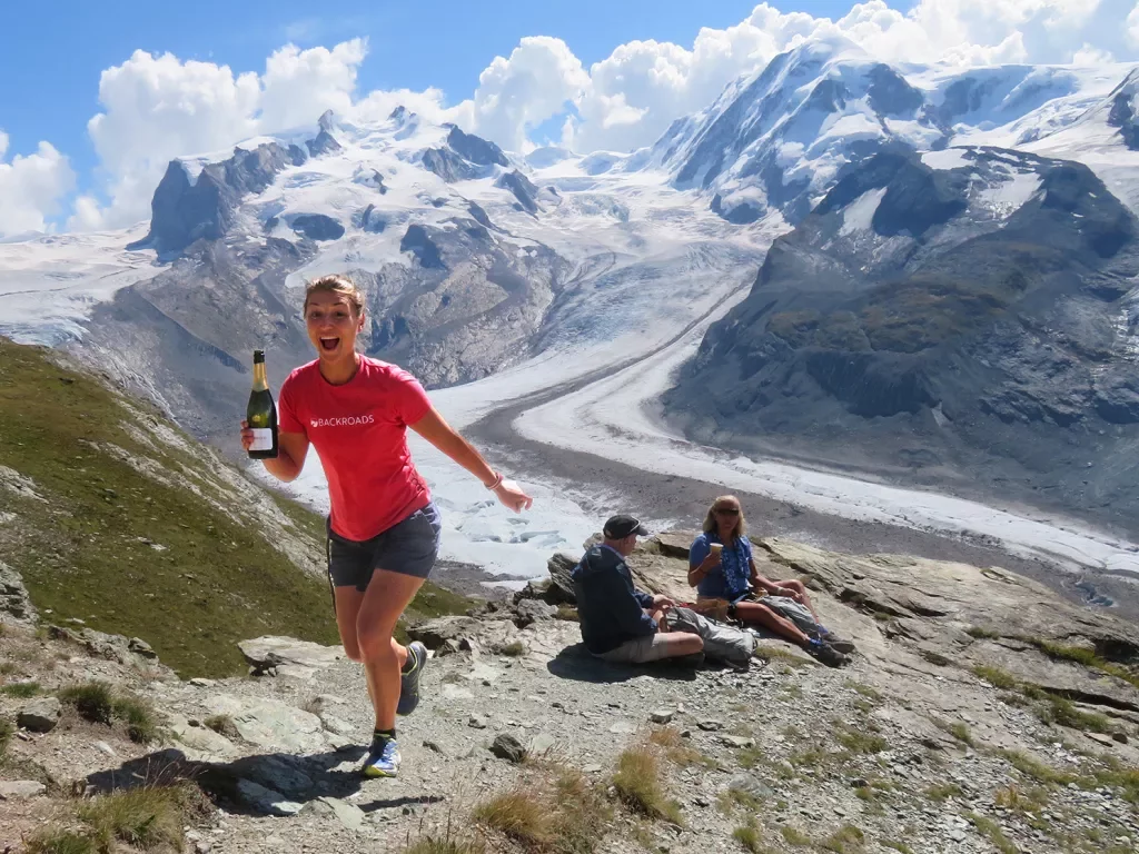 Woman holding a bottle of wine ascending a mountain