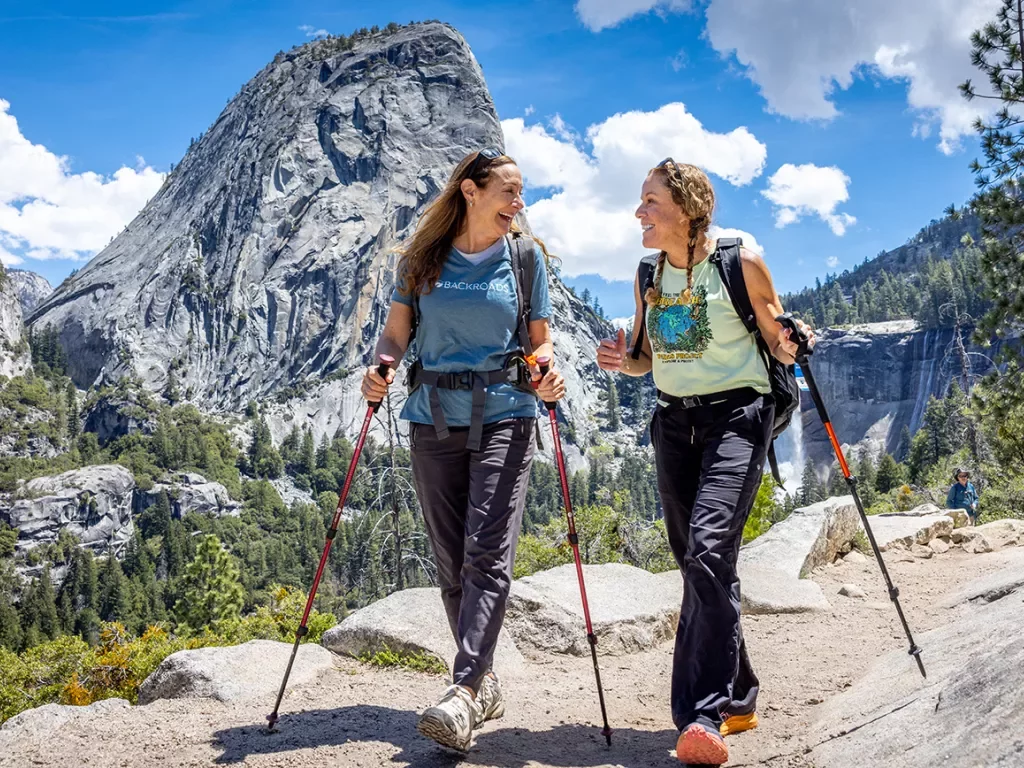 two women with hiking poles hike in yosemite