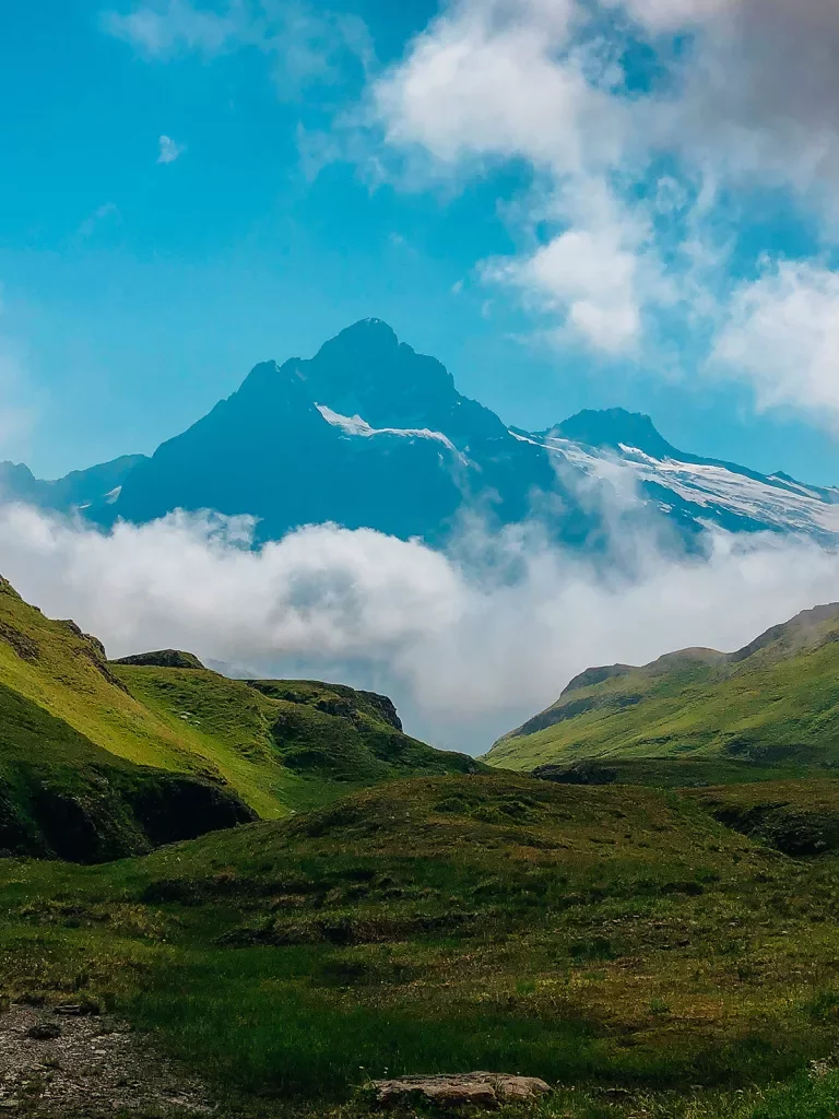 Valley view of Alpine mountains and clouds at the base.