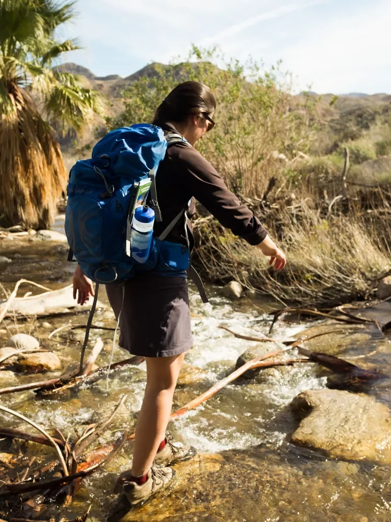 Woman hiker walking through a stream