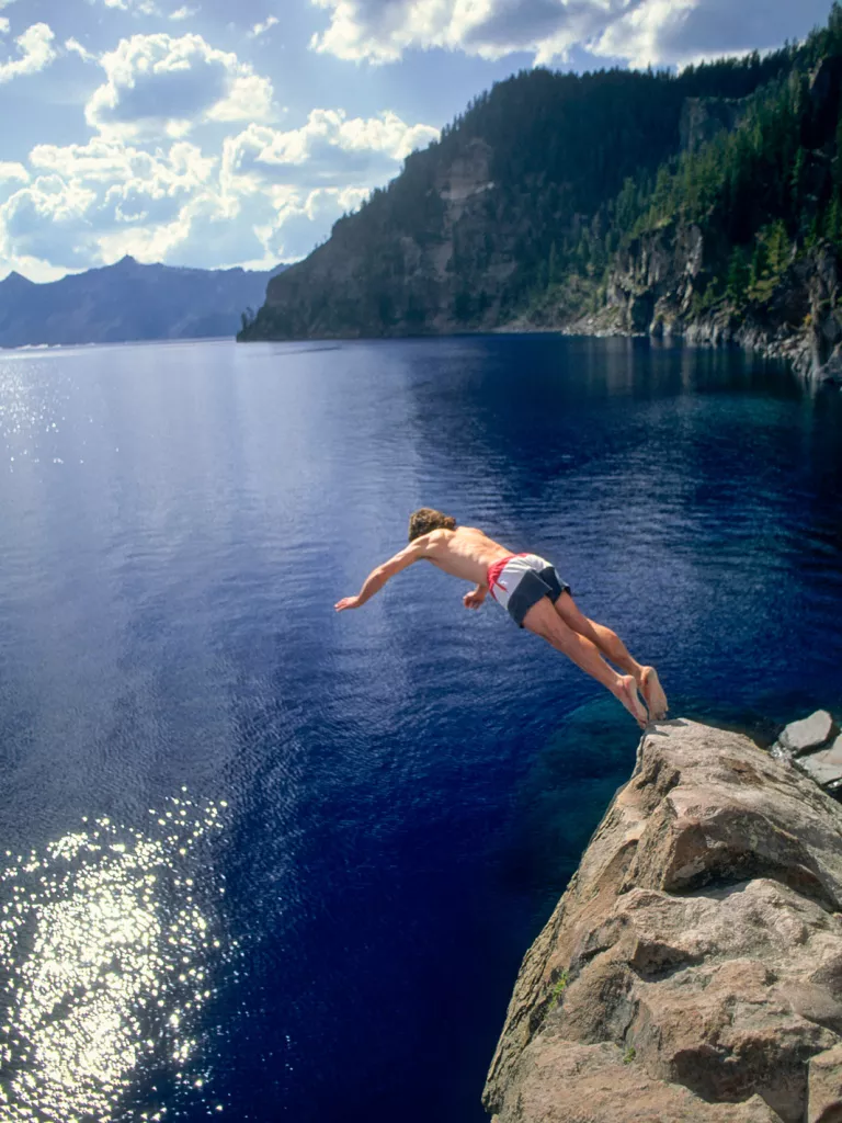 Man jumping of a cliff into a lake