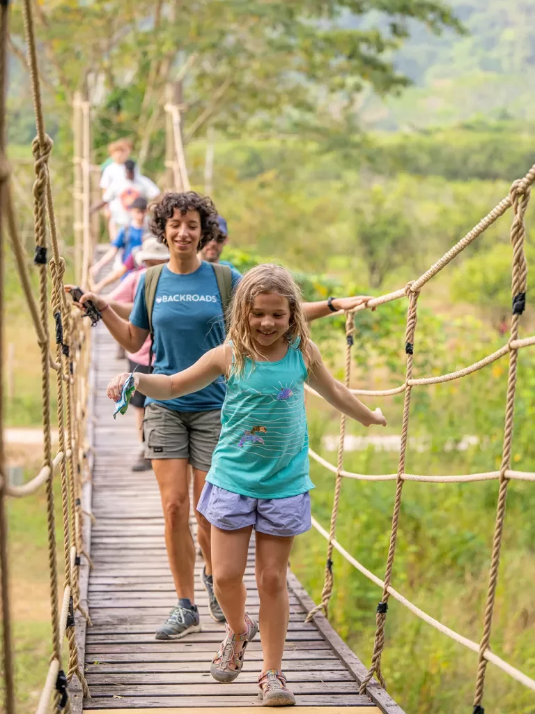 Group of hikers and children on a wooden rope bridge
