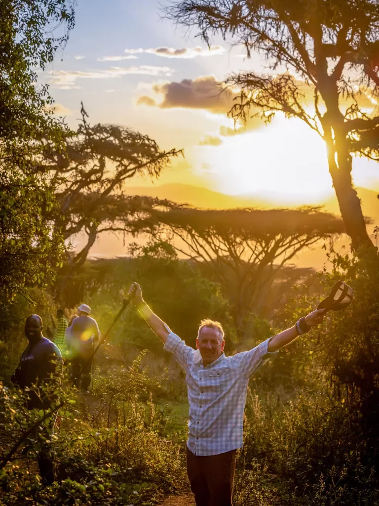 a man poses in front of a sunset