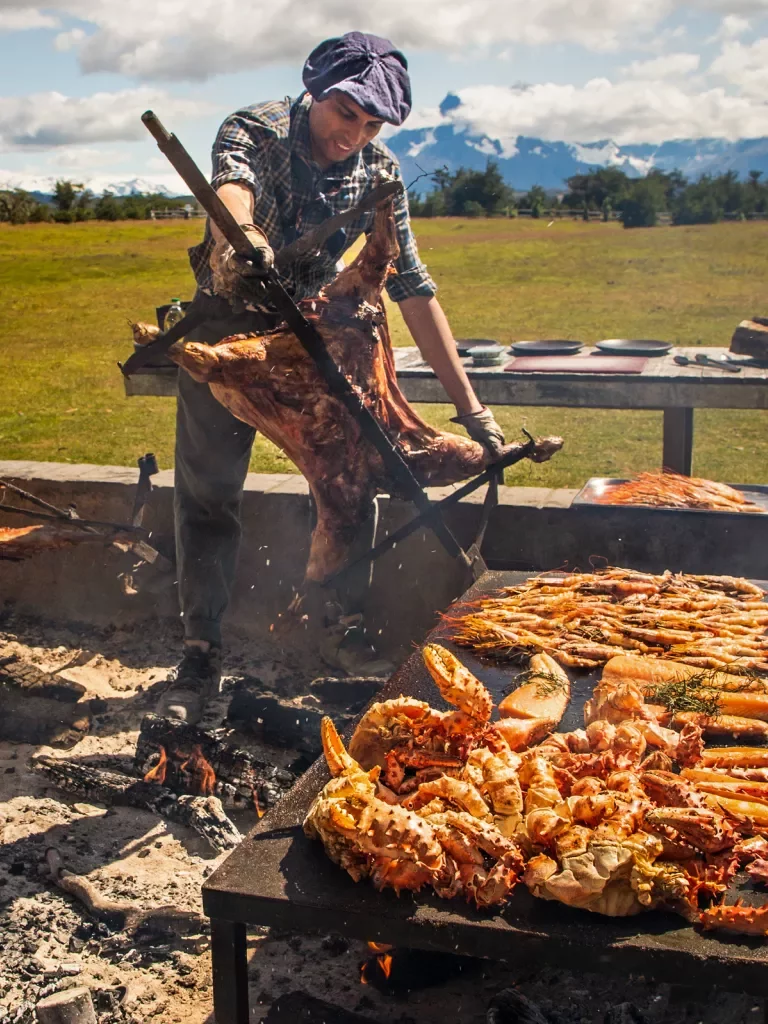 Man grilling seafood while carrying a pig on a rotisserie