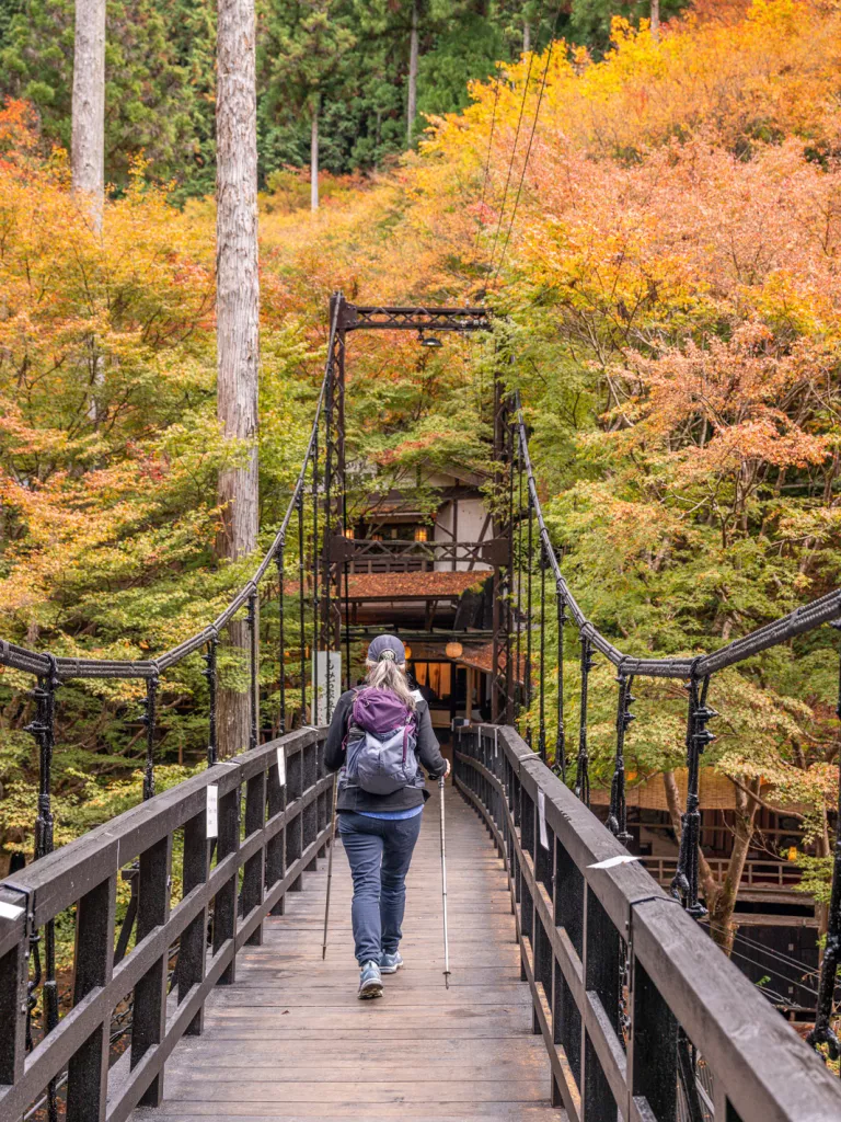 Woman with hiking poles crossing a bridge