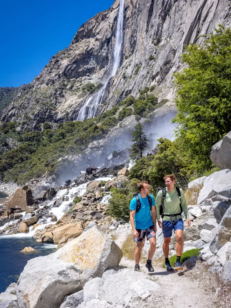 two hikers walk up a rocky trail